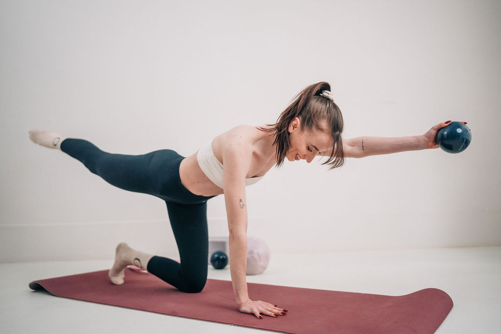 Woman practising Pilates on a mat in a warm, light-filled space